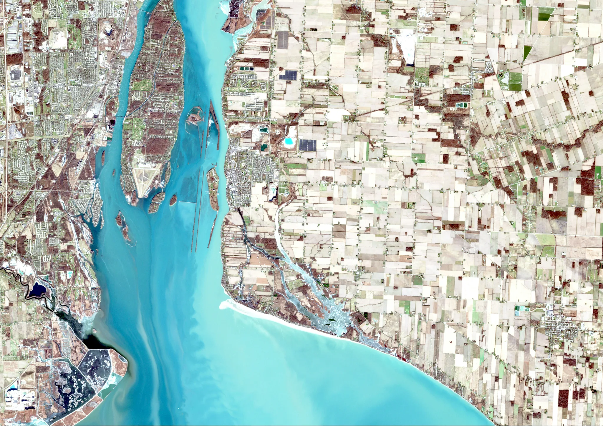 A satellite view of a river mouth and coastline beside farmland and towns